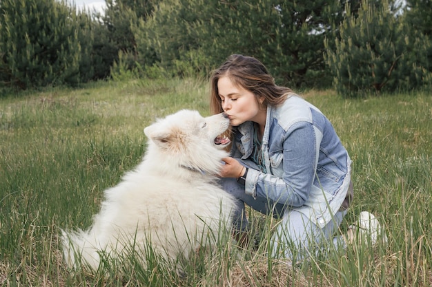 Foto frau, die ihren hund samojede küsst