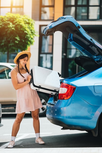 Frau, die ihren Koffer in den Kofferraum des Autos packt