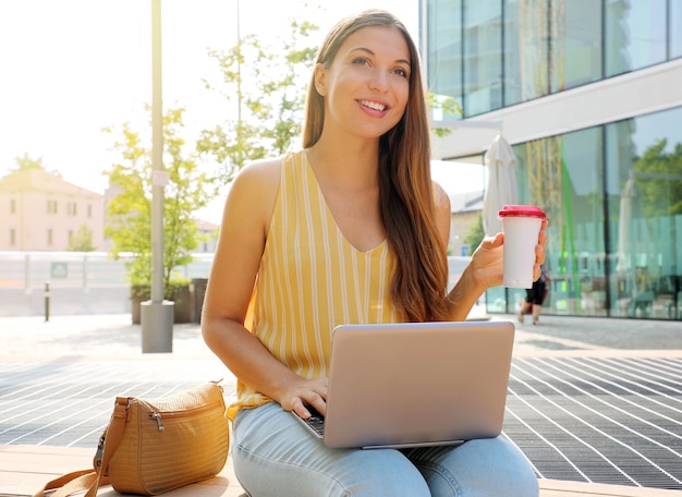 Frau, die ihren Laptop beim Sitzen im Freien verwendet