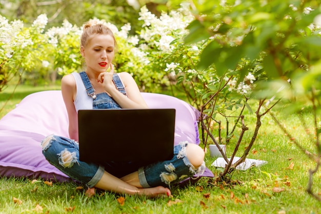 Frau, die ihren Laptop im Garten benutzt