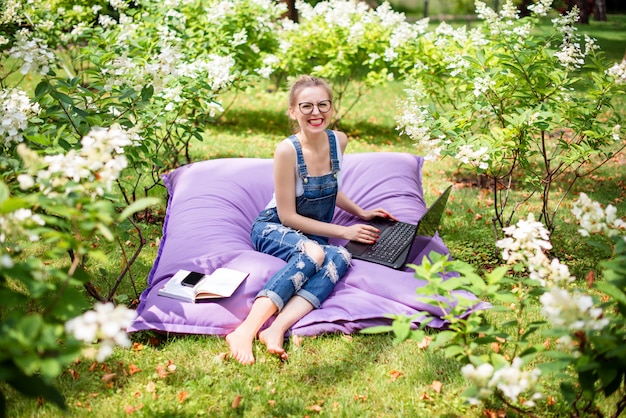 Foto frau, die ihren laptop im garten benutzt