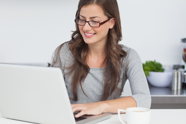 Frau, die ihren Laptop in der Küche verwendet