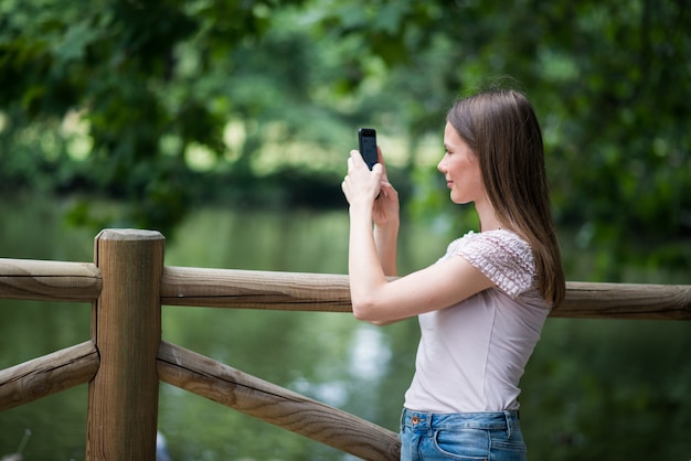 Frau, die ihren Smartphone in einem Park verwendet