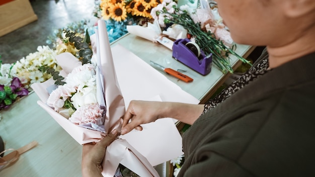 Frau, die im Blumenladen arbeitet und Bestellung Flanellblume in einem Tischarbeitsplatz vorbereitet