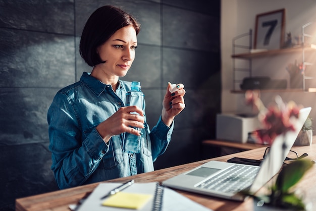 Frau, die im Büro und im Trinkwasser arbeitet