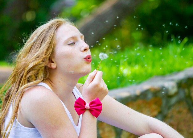 Foto frau, die im freien löwenzahn bläst