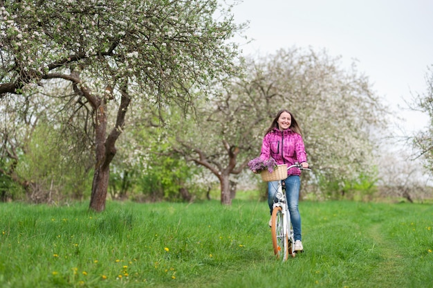 Frau, die im Frühjahr einen weißen Garten des Fahrrades der Weinlese fährt