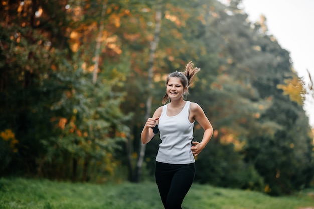 Frau, die im Herbstfallwald läuft. Gesunder Lebensstil . Fit ethnisches kaukasisches Fitness-Modell.