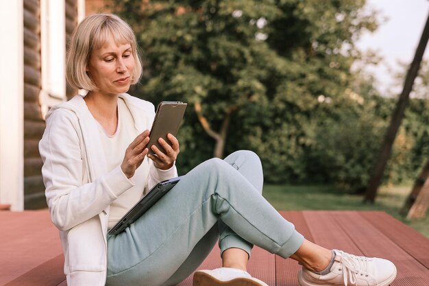 Frau, die im Park mit Telefon und Laptop arbeitet Geschäftsfrau arbeitet im Freien, grüner Naturhintergrund Wi-Fi-Netzwerkverbindung, freier Zugang Freiberufler, der sich in der Natur entspannt und Technologie nutzt