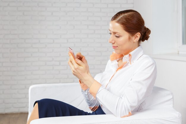 Frau, die im sofa spricht am mobiltelefon sich entspannt