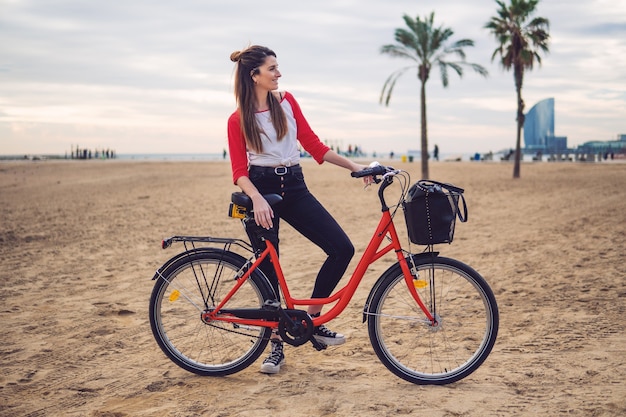 Frau, die im Sommer Fahrrad am Strandsand reitet. Gesundes und sportliches Konzept