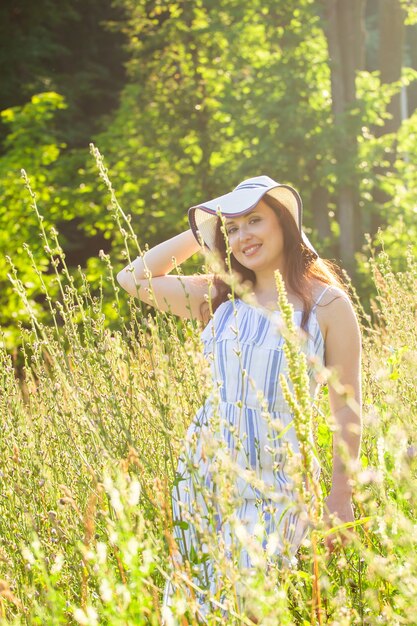 Frau, die im sonnigen Sommertag auf einem Feld geht.