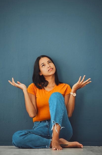 Frau, die im Studio nachdenkt und hinterfragt, warum sie Zweifel hat, Ideen und Entscheidungen über Mockup-Hintergrund Verwirrtes weibliches Modell mit achselzuckendem Brainstorming und visionärer Denkweise der Lösungswahl und Gedanken