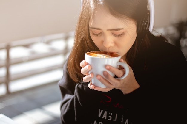 Frau, die im Urlaub einen heißen Kaffee trinkt und Musik hört und sich entspannt