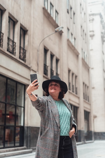 Frau, die im Winter ein Foto auf einer Straße mit alten Gebäuden macht Platz kopieren