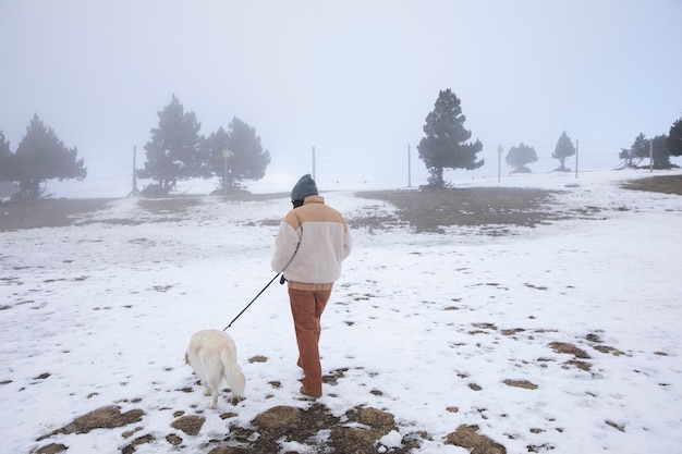 Foto frau, die im winter mit ihrem hund spazieren geht