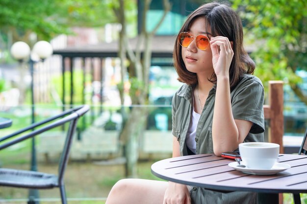 Frau, die in Caféterrasse mit Kaffeetasse sitzt