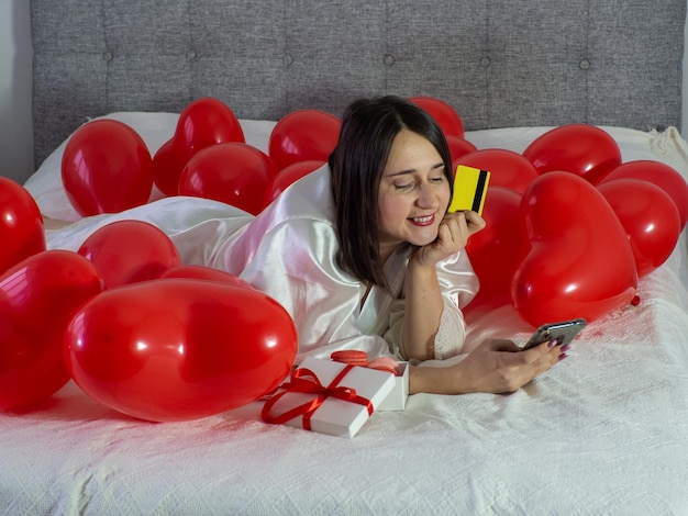 Frau, die in Dekorationen mit Luftballons für die Valentinstagsparty liegt