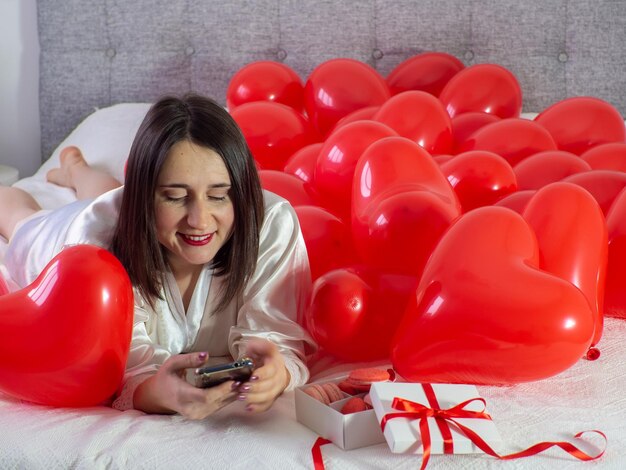 Frau, die in Dekorationen mit Luftballons für die Valentinstagsparty liegt