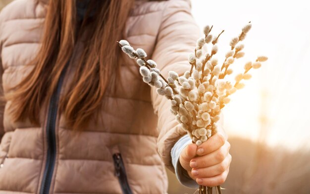 Foto frau, die in der hand bündel weidenkätzchen auf der sonne hält