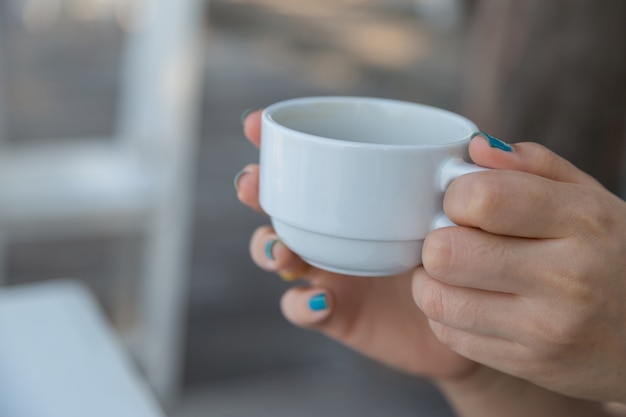 Frau, die in der Hand Kaffee mit Unschärfe baclground trinkt