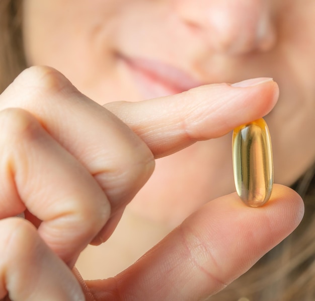 Foto frau, die in der hand omega-3-weichgelkapsel hält. nahaufnahme, selektiver fokus. foto in hoher qualität