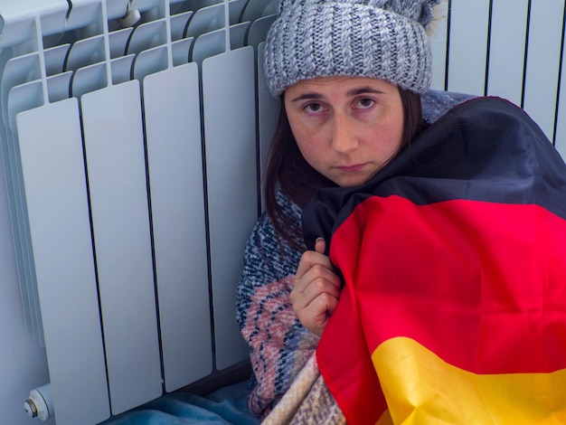 Frau, die in der Nähe der Batterie sitzt und mit deutscher Flagge bedeckt ist