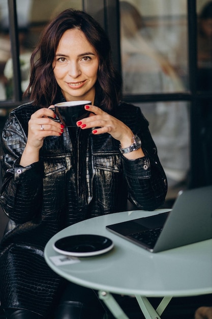 Frau, die in einem Café am Computer arbeitet und Kaffee trinkt