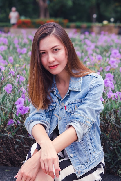 Frau, die in einem Park sitzt, in dem Blumen schön blühen.