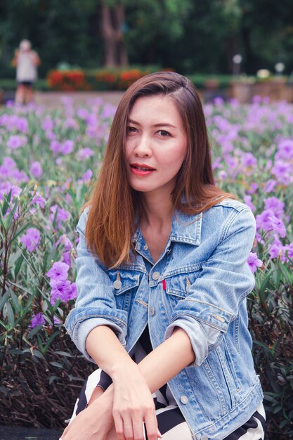 Frau, die in einem Park sitzt, in dem Blumen schön blühen.