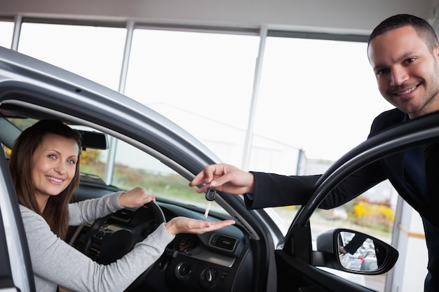 Frau, die in ihrem Auto beim Helfen ihrer Hand sitzt