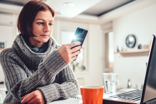 Frau, die intelligentes Telefon im Büro verwendet