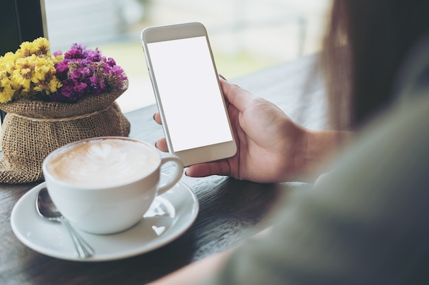 Frau, die intelligentes Telefon verwendet und auf ein Notizbuch schreibt