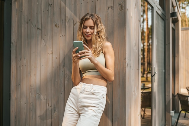 Frau, die interessiert auf Smartphone-Bildschirm schaut