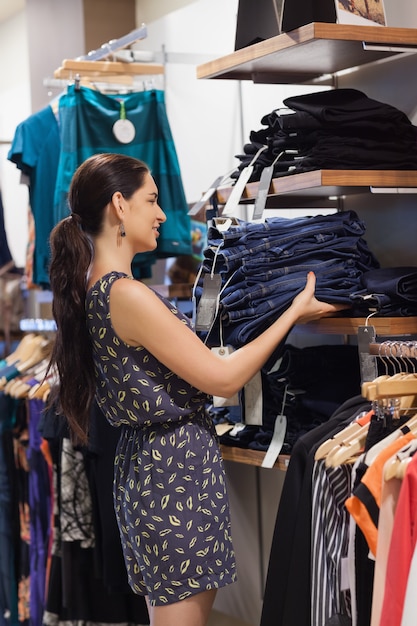 Frau, die Jeans auf Regal setzt