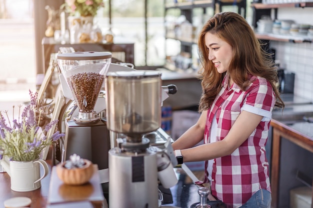 Frau, die Kaffee mit Maschine im Café zubereitet