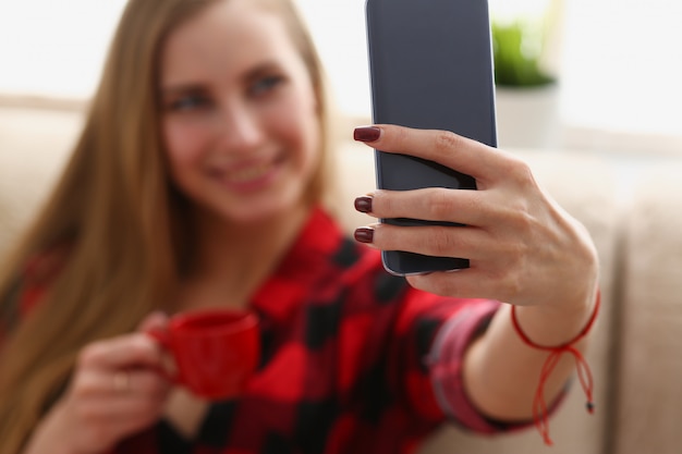 Frau, die Kaffee trinkt und Laptop betrachtet