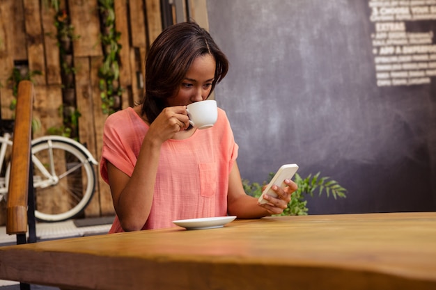 Frau, die Kaffee trinkt und Smartphone verwendet