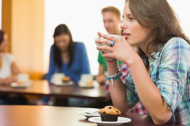 Frau, die Kaffee und Muffin an der Kaffeestube isst