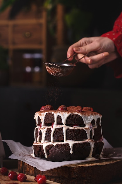 Frau, die Kakaopulver über Kuchen siebt