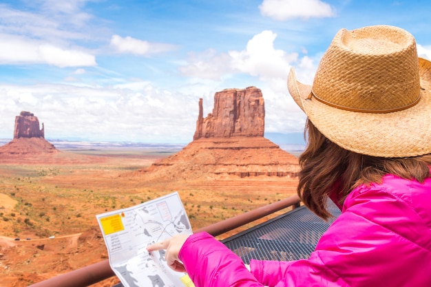 Frau, die karte im monument-tal mit rotem felsenüberblick in arizona usa sitzt und betrachtet