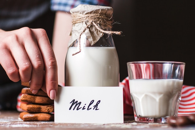 Frau, die Karte nahe Flasche Milch hält.