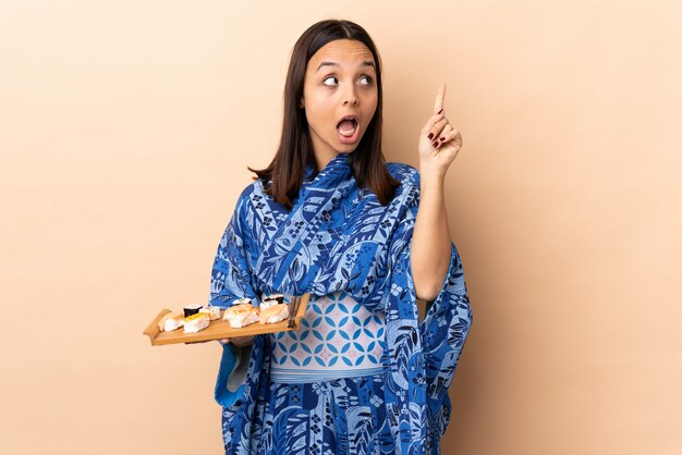 Frau, die Kimono trägt und Sushi über Wand hält, um die Lösung zu realisieren, während sie einen Finger anhebt