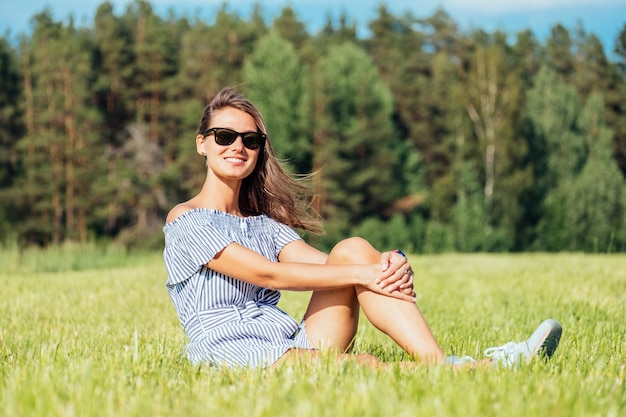 Frau, die Kleid sitzt auf grünem Grasfeld