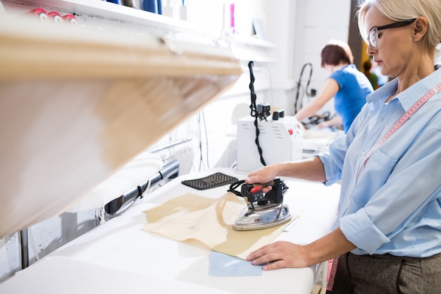 Frau, die Kleidung im Atelier bügelt