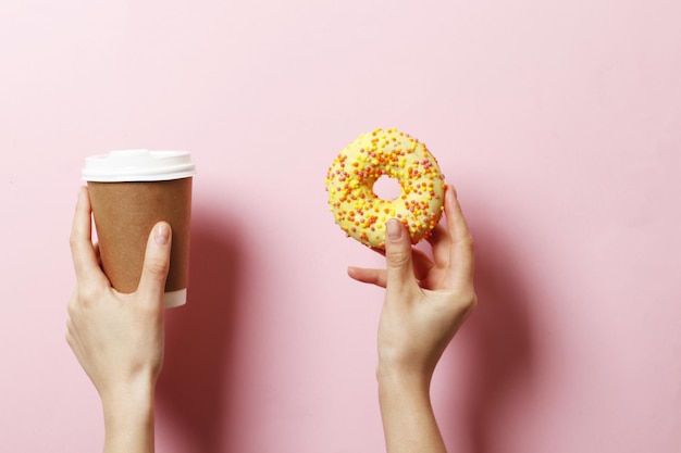 Frau, die köstlichen Donut und Kaffee auf Farbhintergrund hält