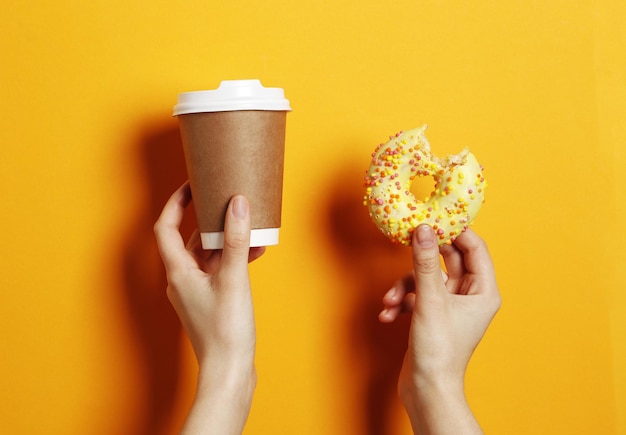 Frau, die köstlichen Donut und Kaffee auf Farbhintergrund hält