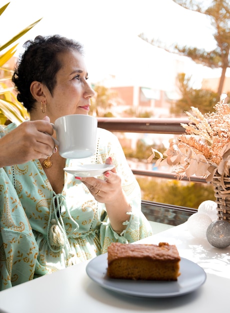 Frau, die Krebs überwunden hat, trinkt einen Kaffee auf ihrer Terrasse.