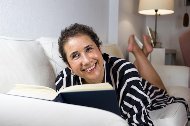 Frau, die Krebs überwunden hat und ein Buch auf ihrer Couch liest.