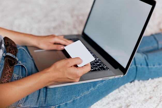 Frau, die Kreditkarte hält und an einem Laptop arbeitet Frau, die einen Laptop sitzt auf dem Boden verwendet